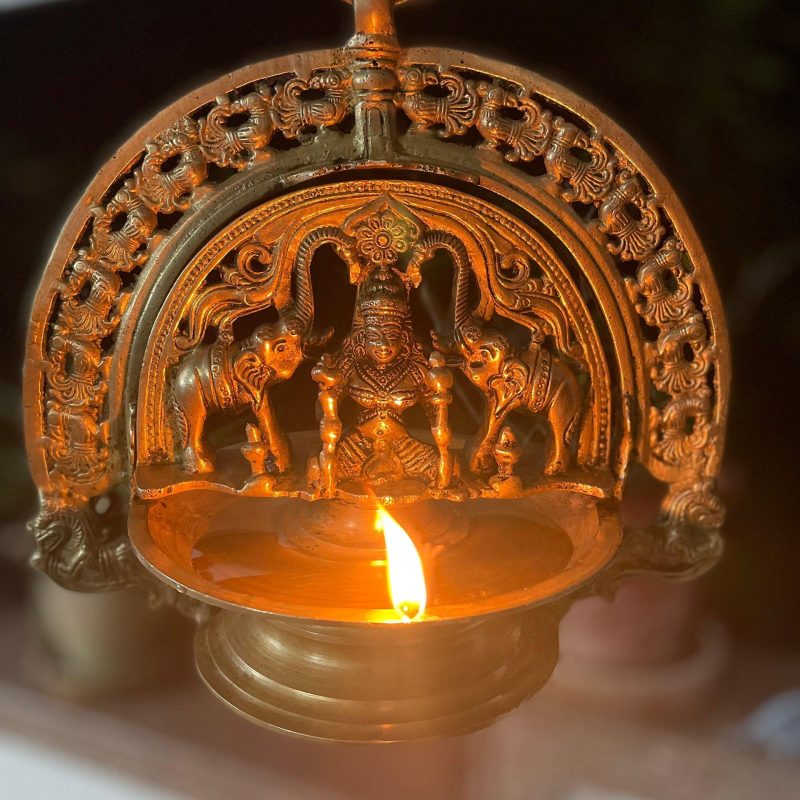 Traditionelle indische Öllampe aus Messing mit brennender Flamme und filigranen Verzierungen
